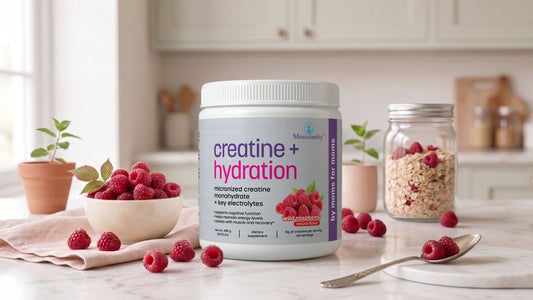 Momsanity Creatine + Hydration tub with fresh raspberries on a kitchen counter